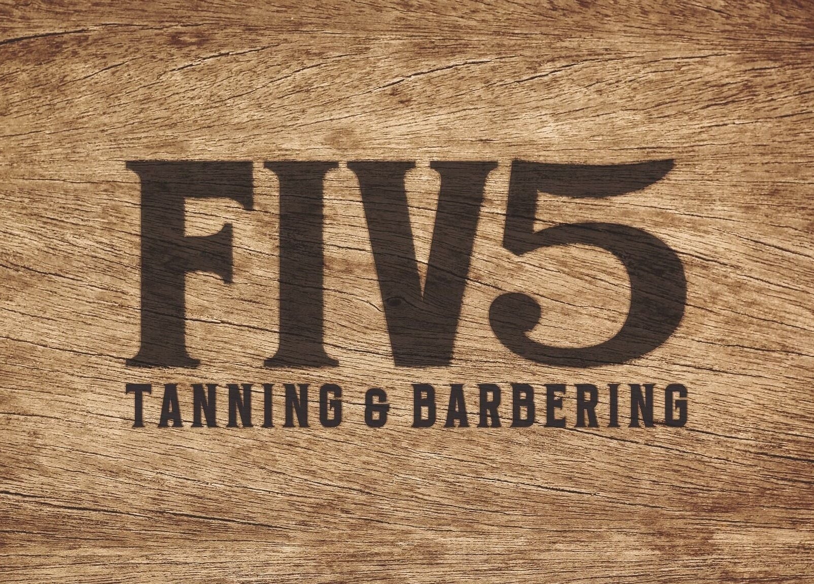FIV5 Tanning & Barbering logo on wood texture, Sandy, England, GB.