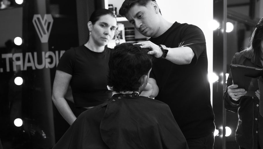 Profesional en Tonny Serrano CR estilizando cabello bajo luces cálidas, creando un ambiente de belleza.