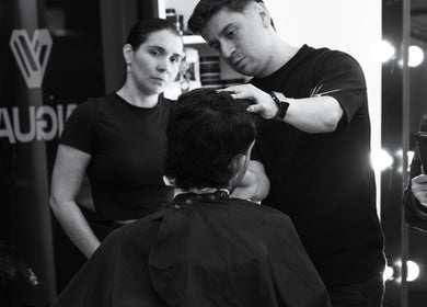 Profesional en Tonny Serrano CR estilizando cabello bajo luces cálidas, creando un ambiente de belleza.