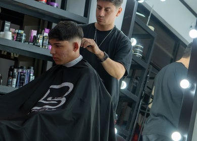 Barbero en Tonny Serrano, CR, realizando un corte moderno en un cliente joven frente al espejo.