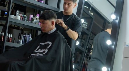 Barbero en Tonny Serrano, CR, realizando un corte moderno en un cliente joven frente al espejo.