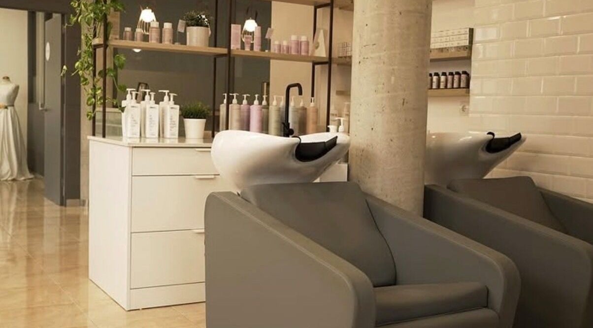 Zona de lavado en Espai I'M en Amposta, Catalunya, ES, con sillones modernos y productos de cuidado.