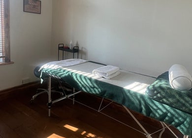 Comfortable massage room at Chin Up Manual Face Therapy, Huddersfield, England, GB, with soft lighting and greenery.