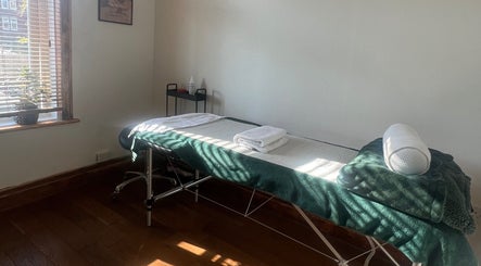 Comfortable massage room at Chin Up Manual Face Therapy, Huddersfield, England, GB, with soft lighting and greenery.