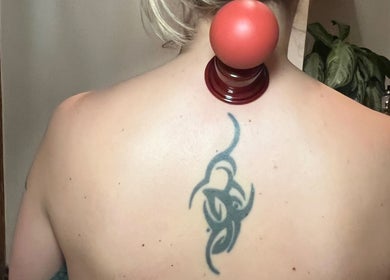 Cupping therapy at Chin Up Manual Face Therapy. Huddersfield, England, GB scene shows back tattoo.