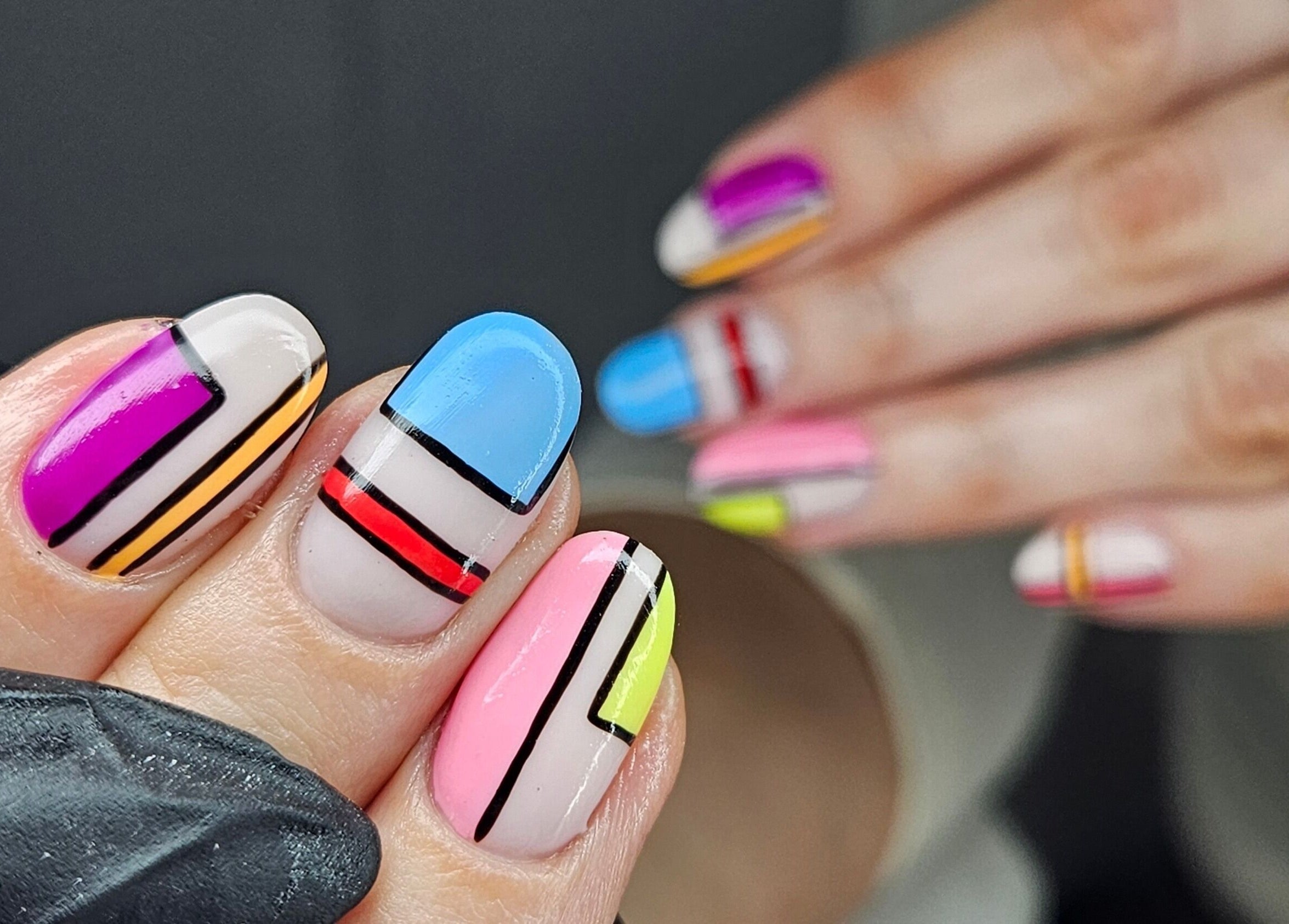 Colorful modern nail art at cwbeautyofficial, Milnrow, England, GB showcasing vibrant geometric designs.