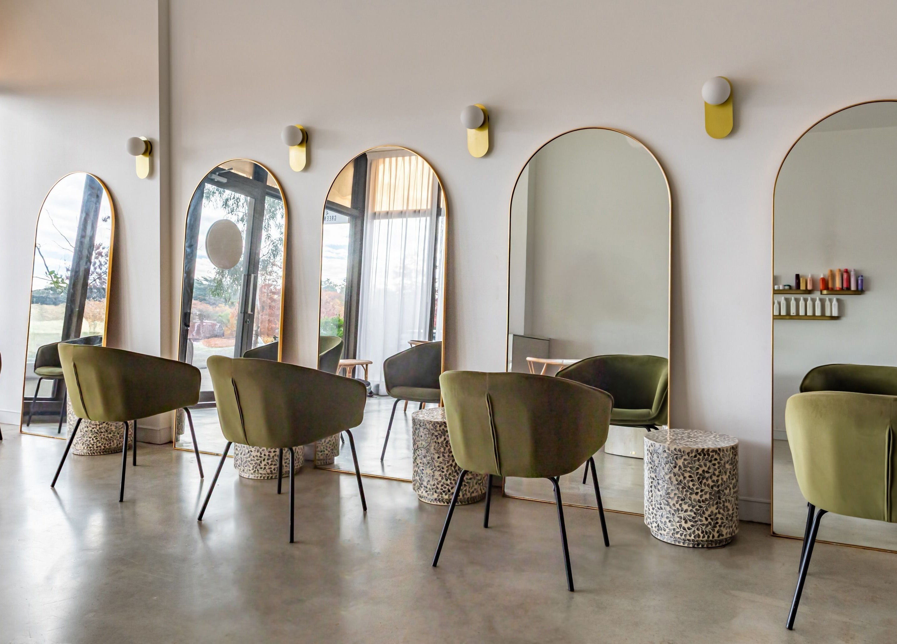Cali Studio at Campbell, AU features chic mirrors and green chairs in a bright, modern interior.