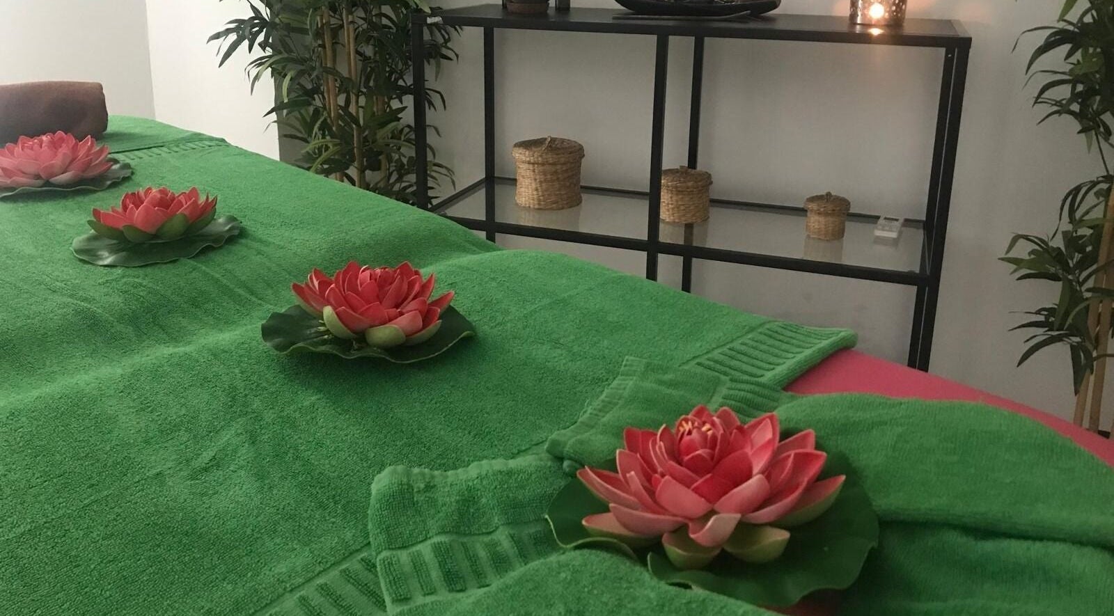 Sala de masajes en Lanzarote Massages, Costa Teguise, Canarias, ES con decoración floral y toallas verdes.