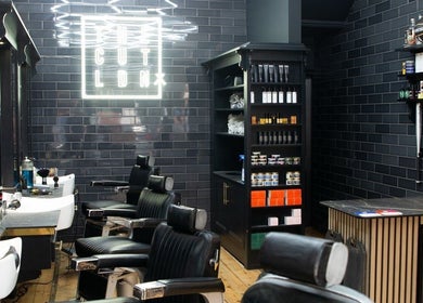 Interior of The Cut LDN barber shop in London, England, GB, featuring stylish black decor and grooming chairs.