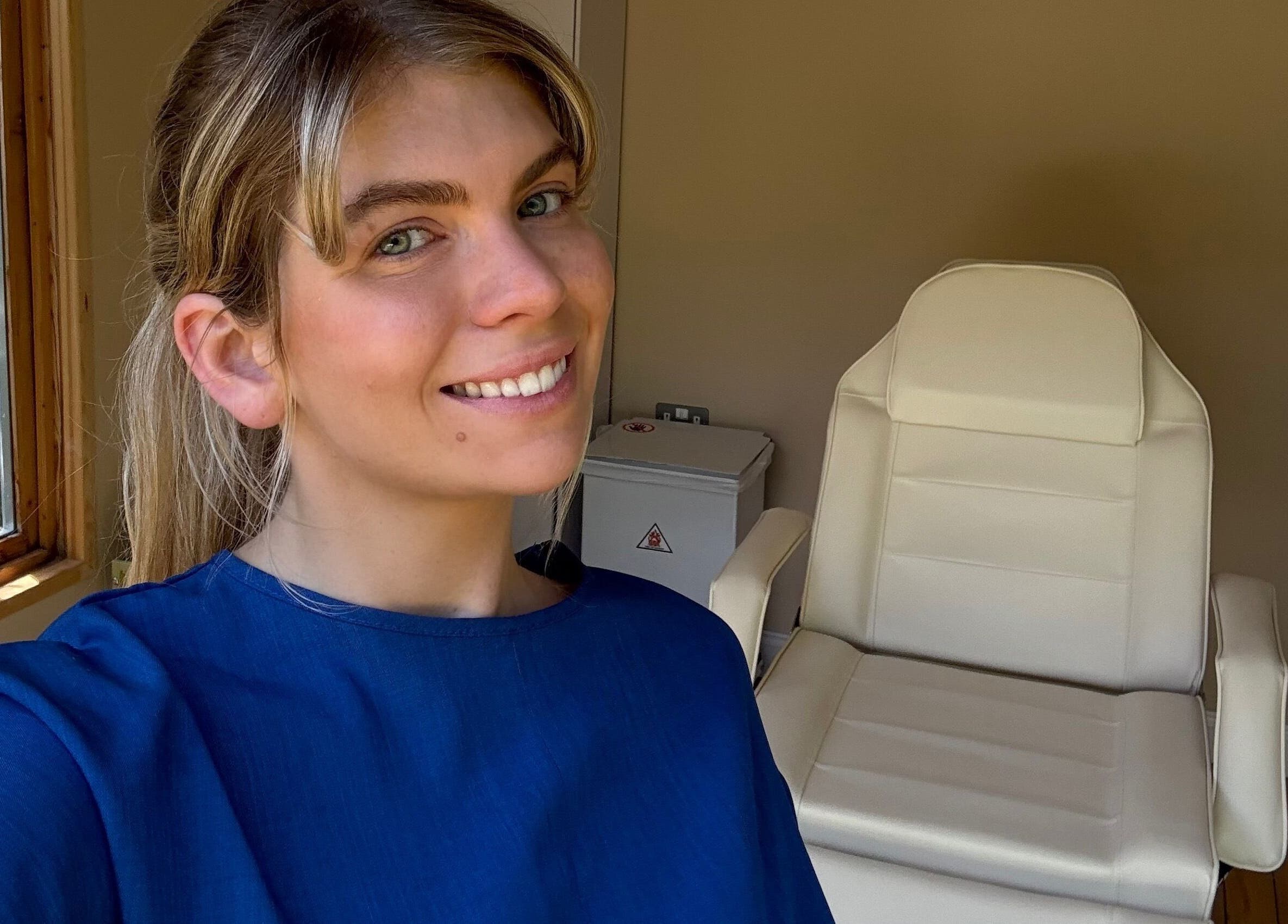 Aesthetician smiling in treatment room at Golden Hour Aesthetics, Derby, England, GB.