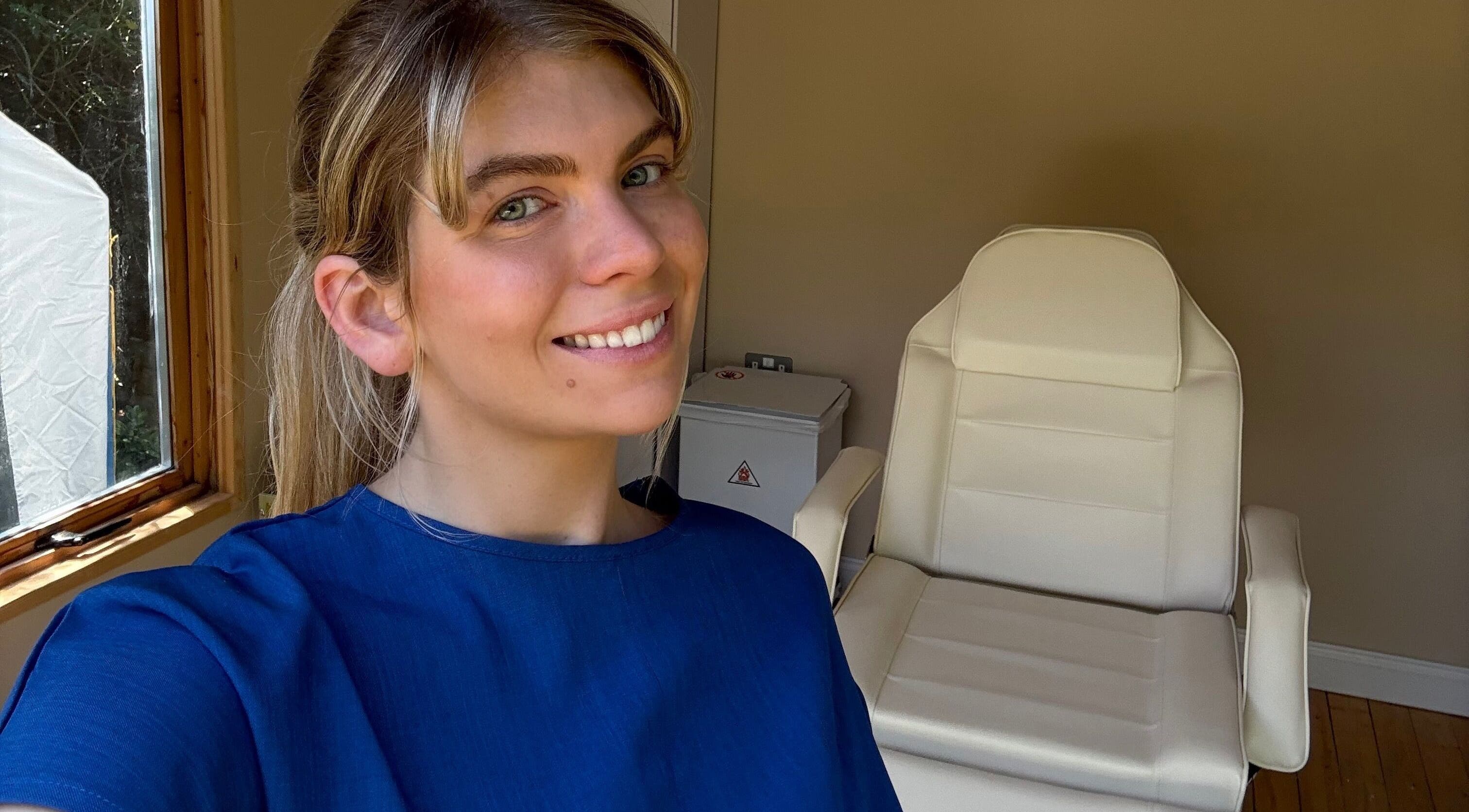 Aesthetician smiling in treatment room at Golden Hour Aesthetics, Derby, England, GB.