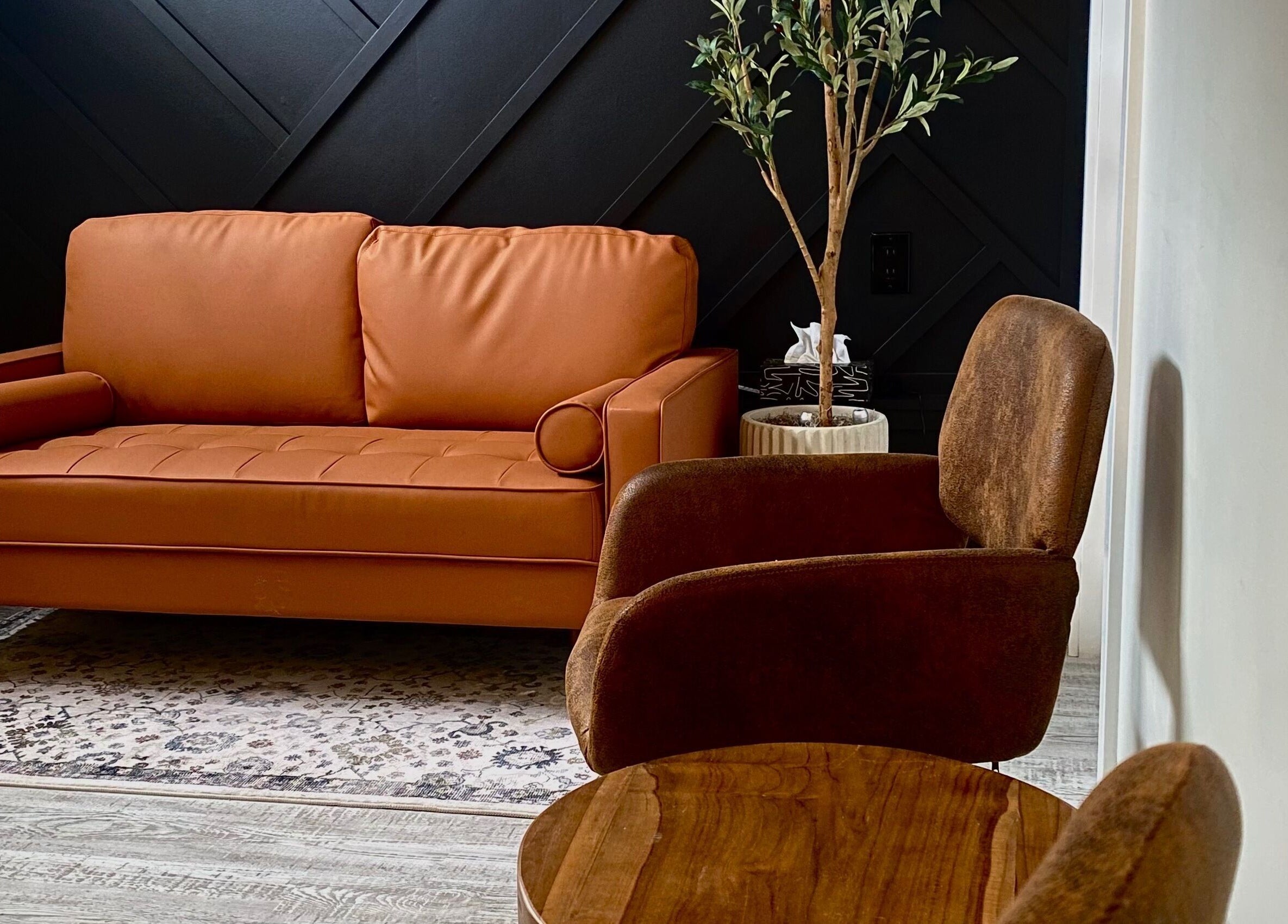 Cozy seating area at Inua Spa, Yarmouth, Nova Scotia, CA, featuring a warm-toned sofa and elegant decor.
