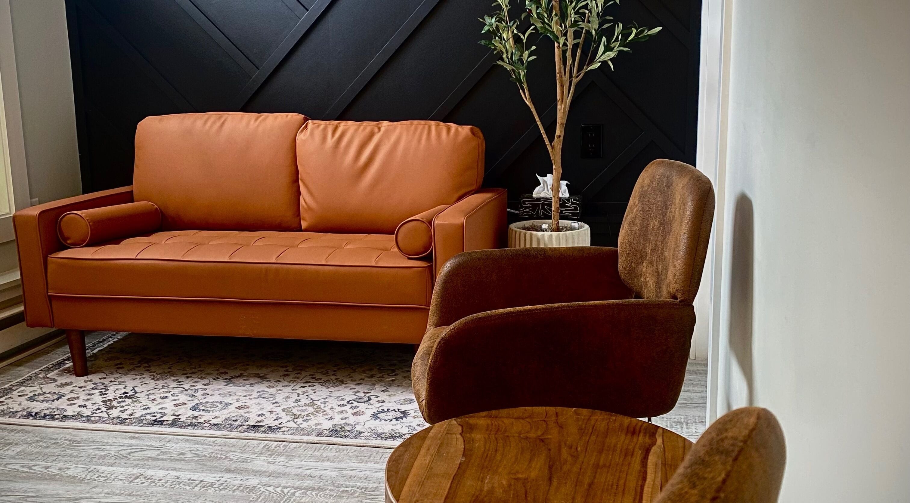 Cozy seating area at Inua Spa, Yarmouth, Nova Scotia, CA, featuring a warm-toned sofa and elegant decor.