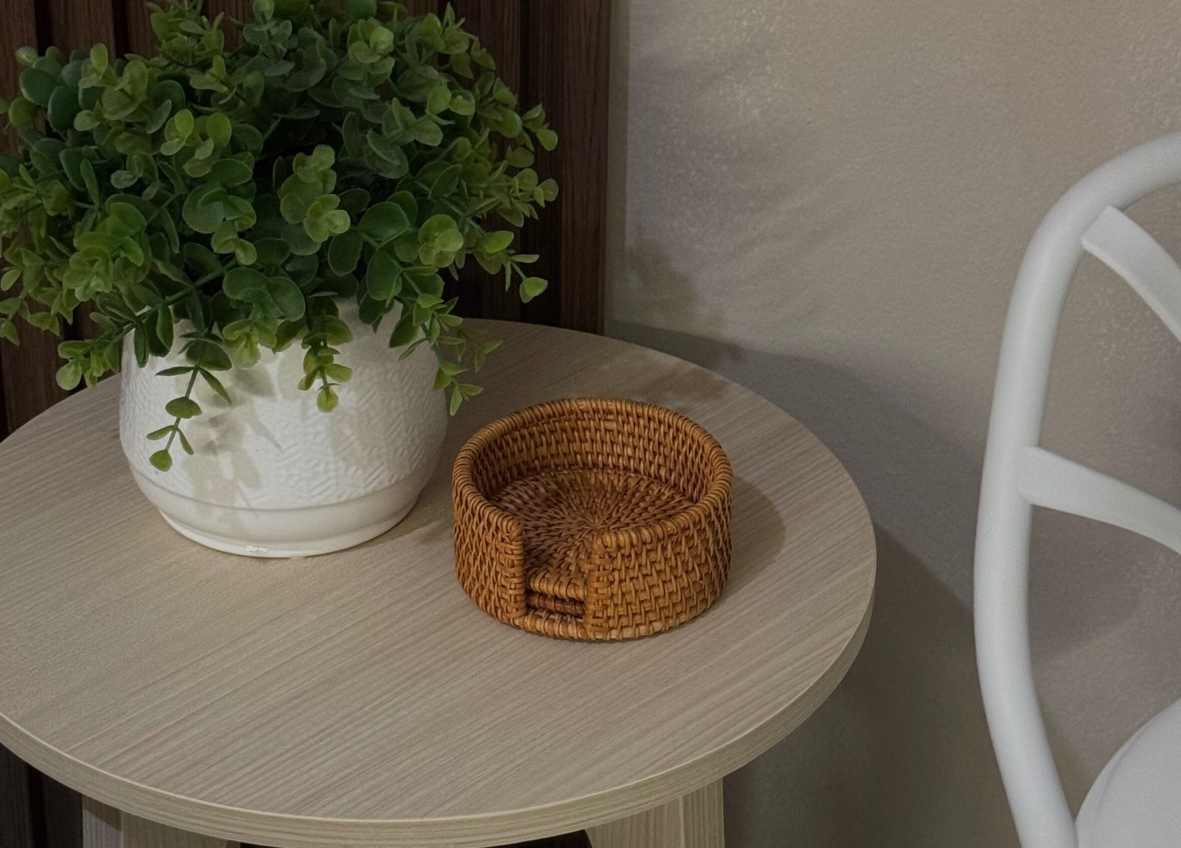 Mesa decorativa en Kare Esthetics, Bayamón, Puerto Rico, PR, con planta verde en maceta blanca y posavasos de mimbre.