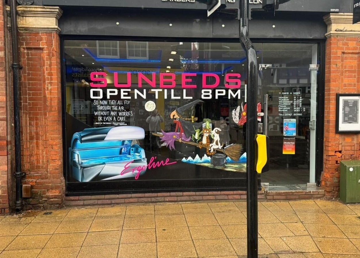Exterior view of Frankies Barbers & Tanning in Biggleswade, England with sunbed signage.