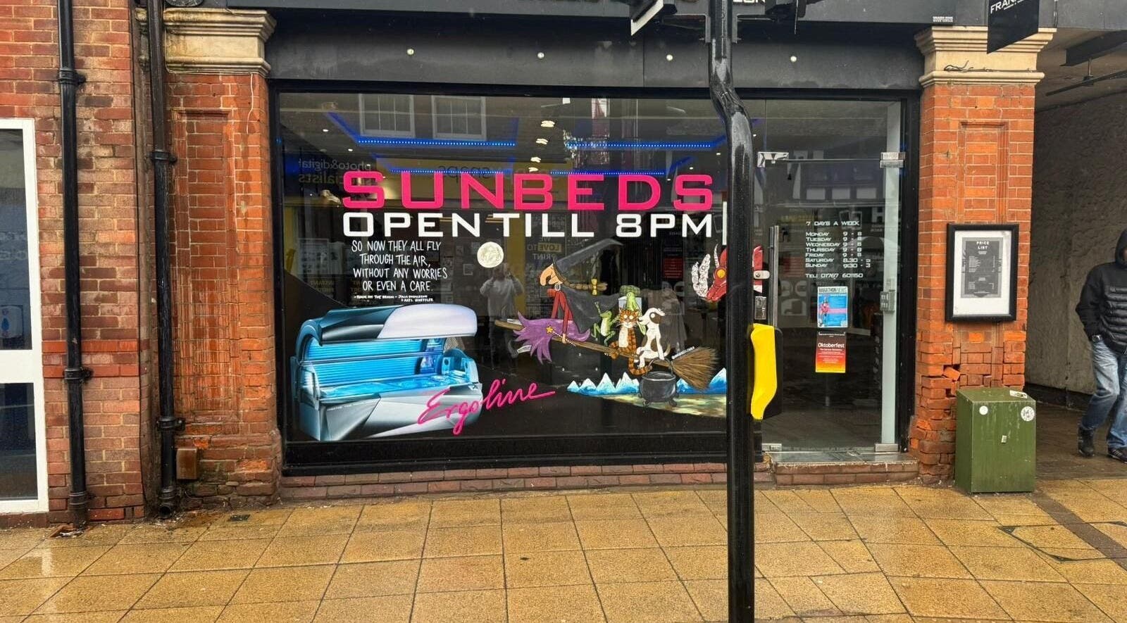 Exterior view of Frankies Barbers & Tanning in Biggleswade, England with sunbed signage.