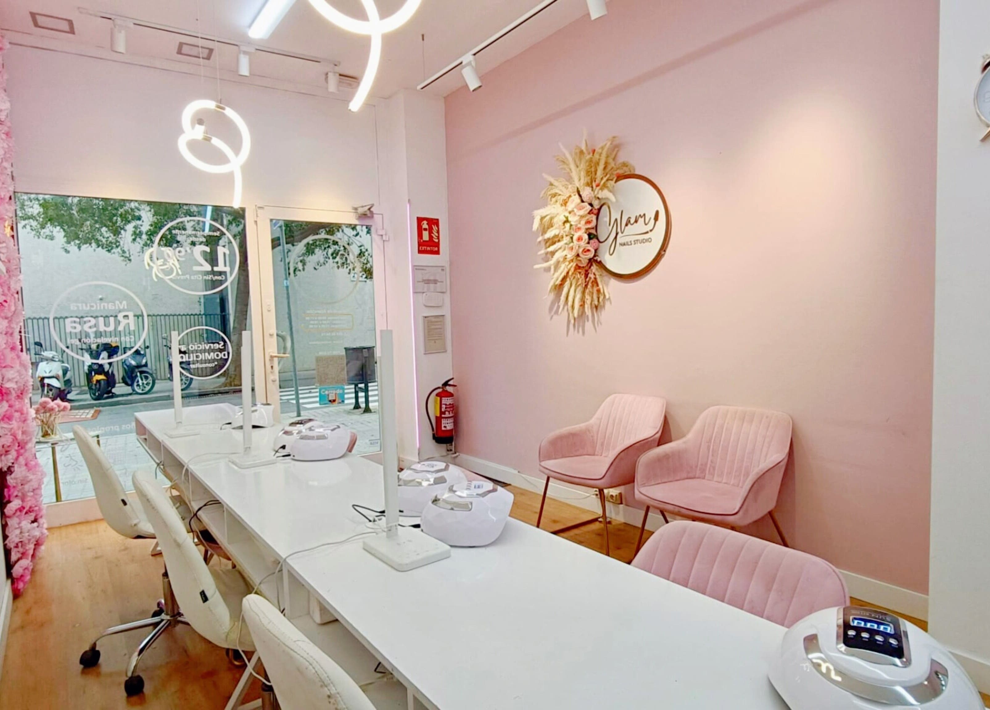 Interior elegante de GLAM Nails Studio - Guillem Tell en Barcelona, Catalunya, ES con decoración moderna y sillas rosas.