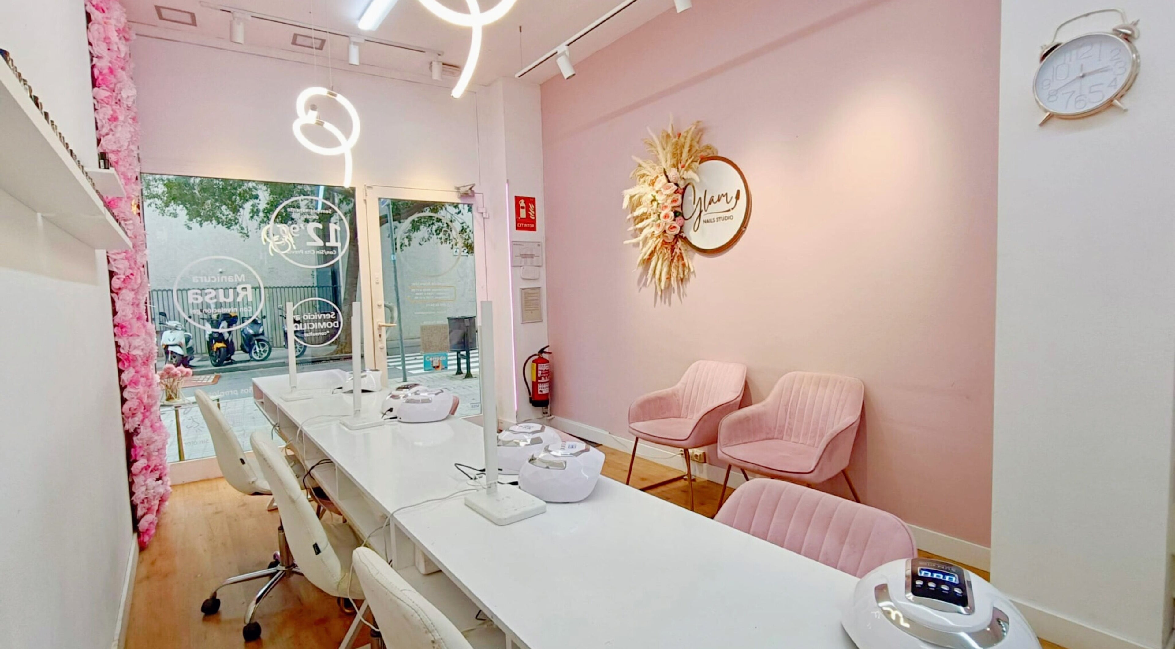 Interior elegante de GLAM Nails Studio - Guillem Tell en Barcelona, Catalunya, ES con decoración moderna y sillas rosas.