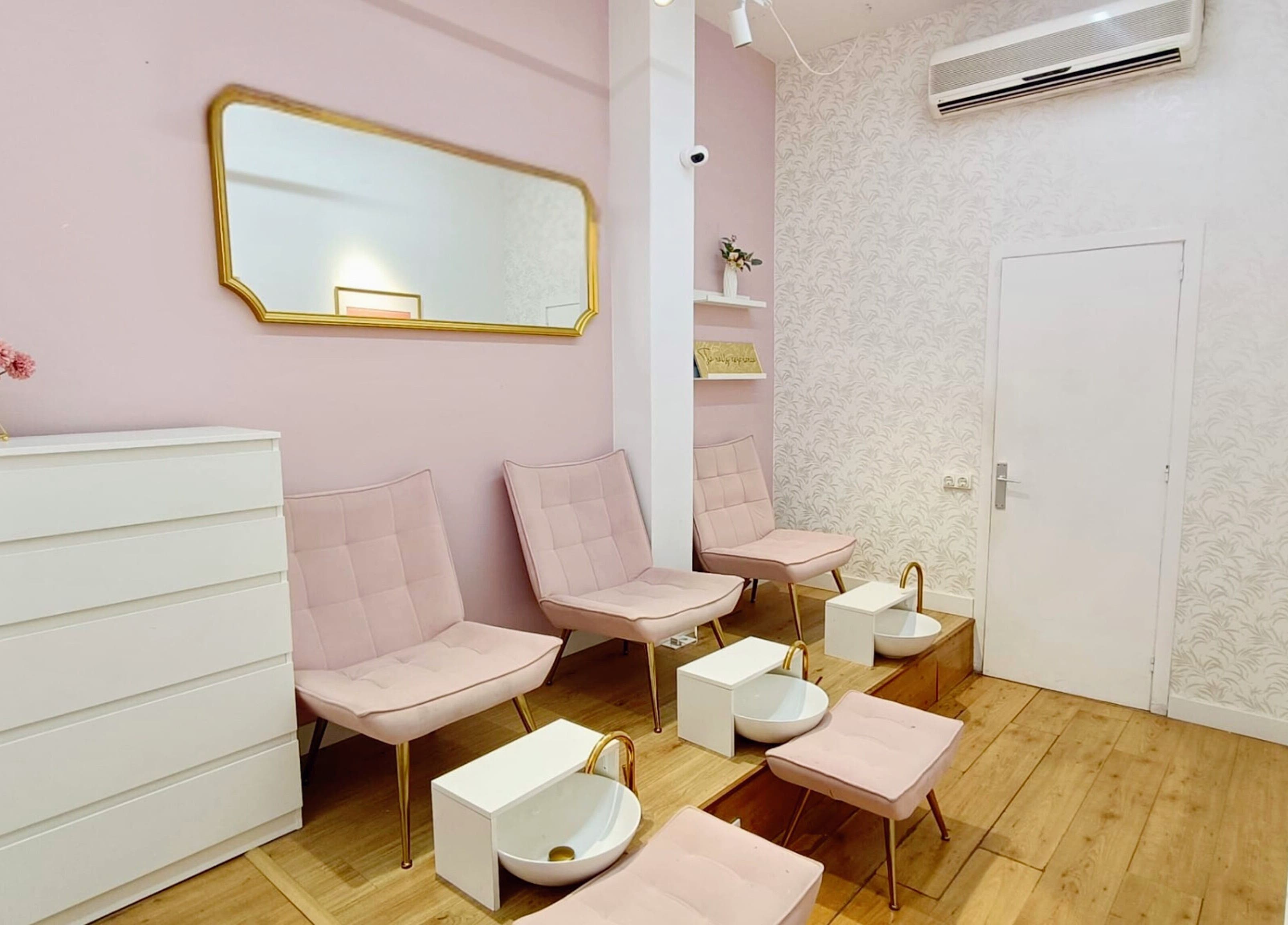 Moderno interior de GLAM Nails Studio - Guillem Tell, en Barcelona, con elegantes sillas rosadas y decoración floral.