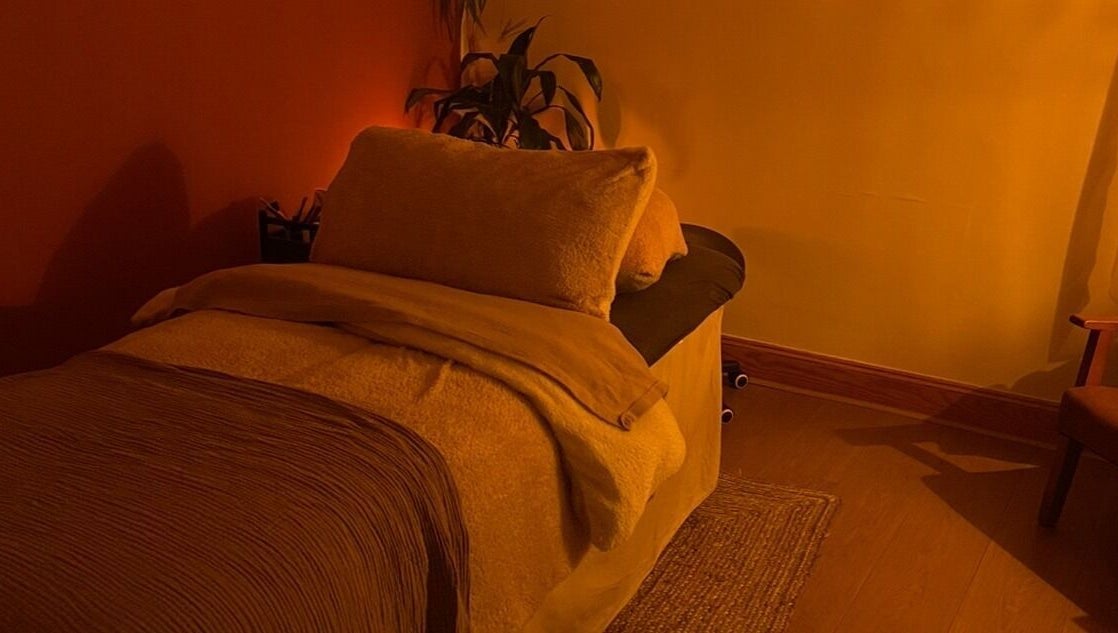 Cozy massage room at Rooted in Rest, Auchterarder, Scotland, GB, with warm lighting and plush bedding.