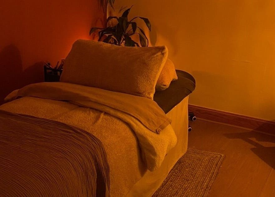 Cozy massage room at Rooted in Rest, Auchterarder, Scotland, GB, with warm lighting and plush bedding.
