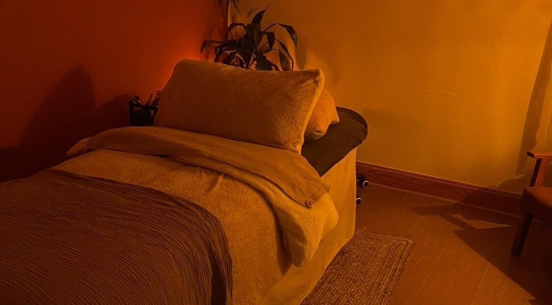 Cozy massage room at Rooted in Rest, Auchterarder, Scotland, GB, with warm lighting and plush bedding.