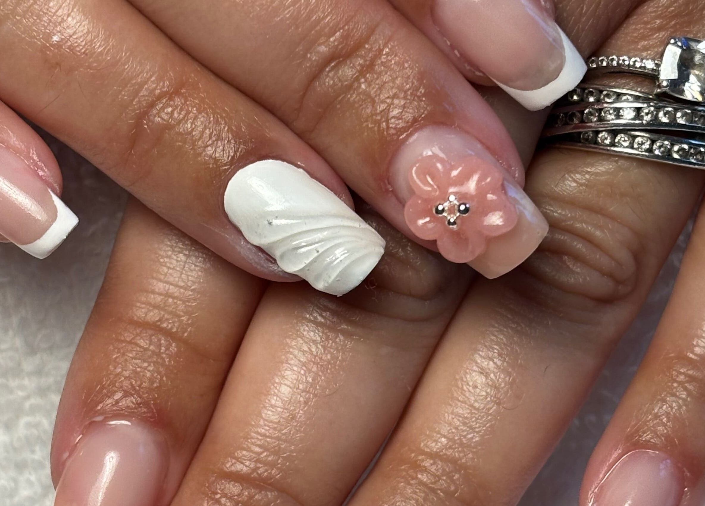 Art&Miss à Chartainvilliers propose une manucure élégante avec des détails floraux et des anneaux scintillants.