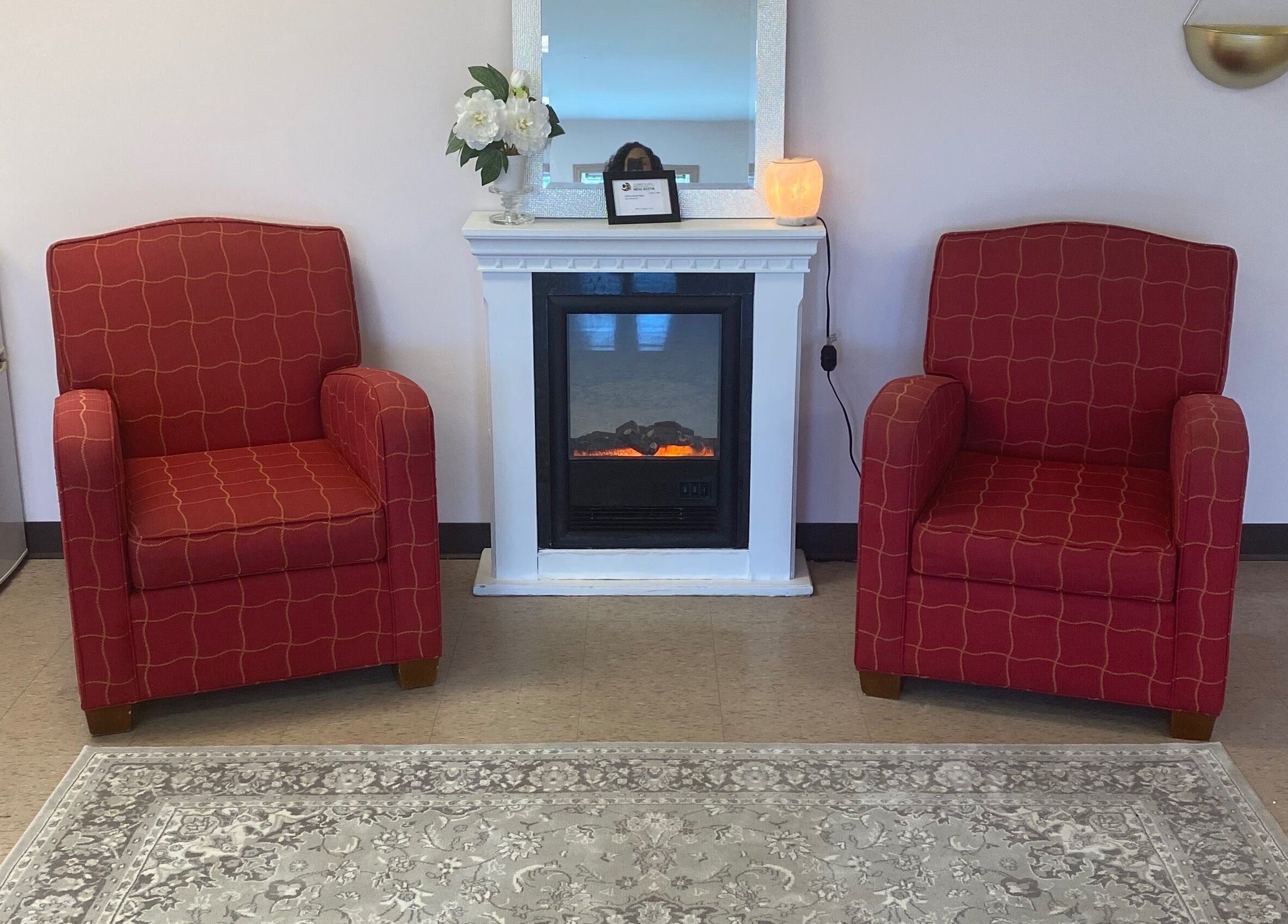 Elegant red chairs flanking a fireplace at Gel Envy - Jasmin Shears, Lower Sackville, Nova Scotia, CA.