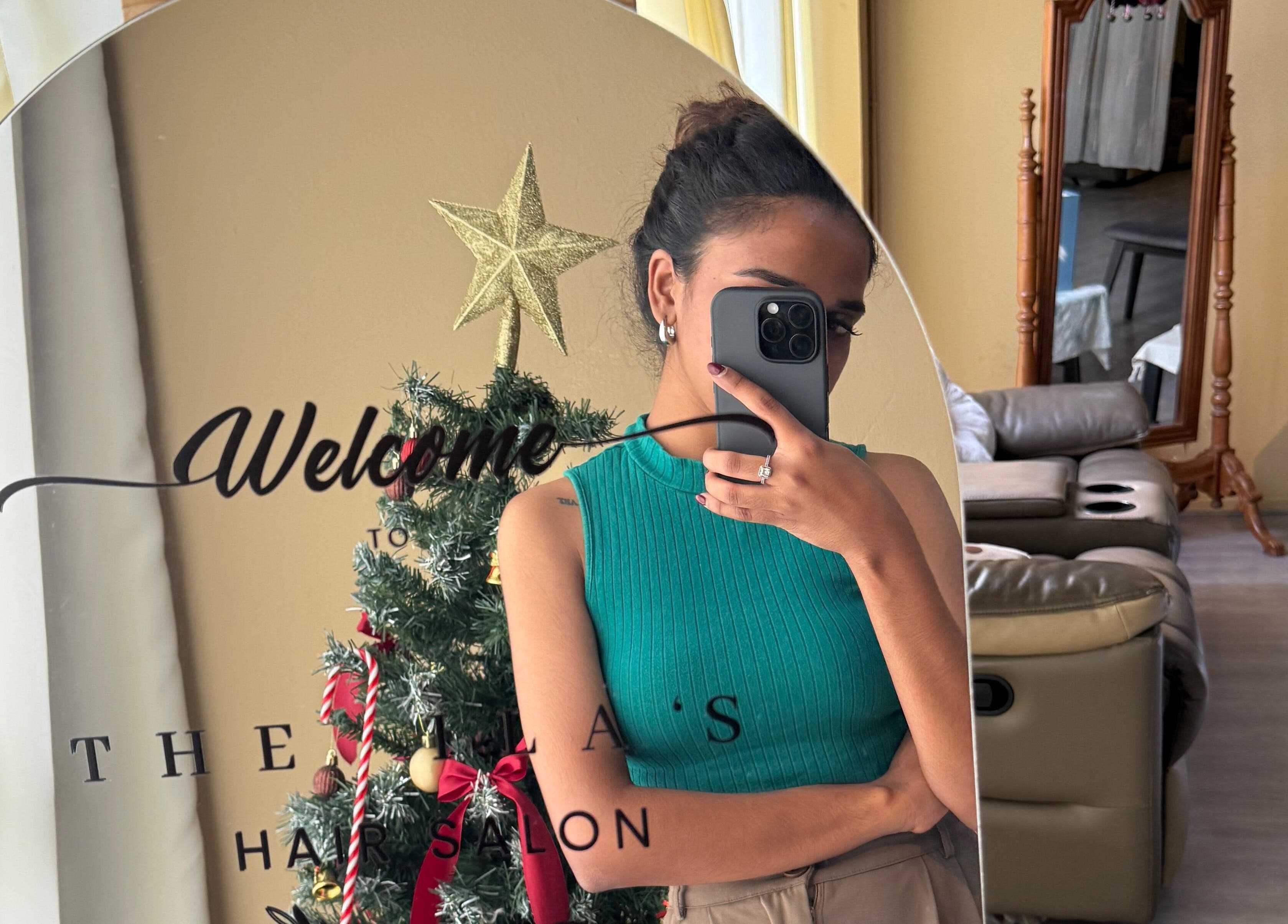 Mirror reflection of a woman at The Ila’s Hair Salon, Kajang, Selangor, MY, near a decorated Christmas tree.
