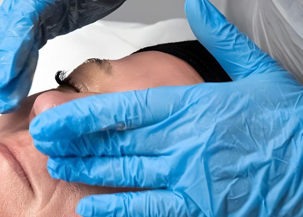 Facial treatment at Reflexions, Hockley, England, GB with blue-gloved hands offering soothing care.