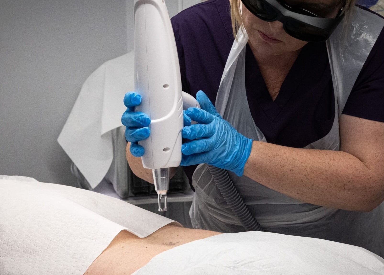 Therapist using laser treatment device at Reflexions, Hockley, England, GB for precise skin care.