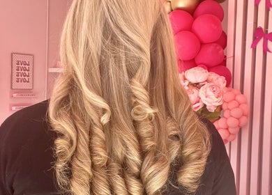 Curly hairstyle at Hair by Susie Hancock in Ferndown, England, GB with pink decorations.