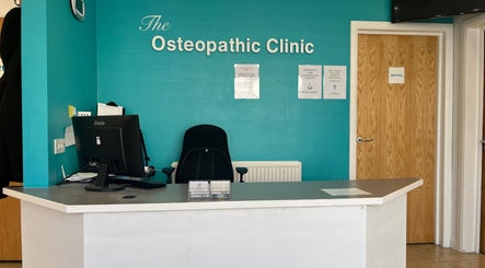 Reception desk at New Barnet Chiropody Clinic in New Barnet, England, GB featuring a teal wall and computer setup.