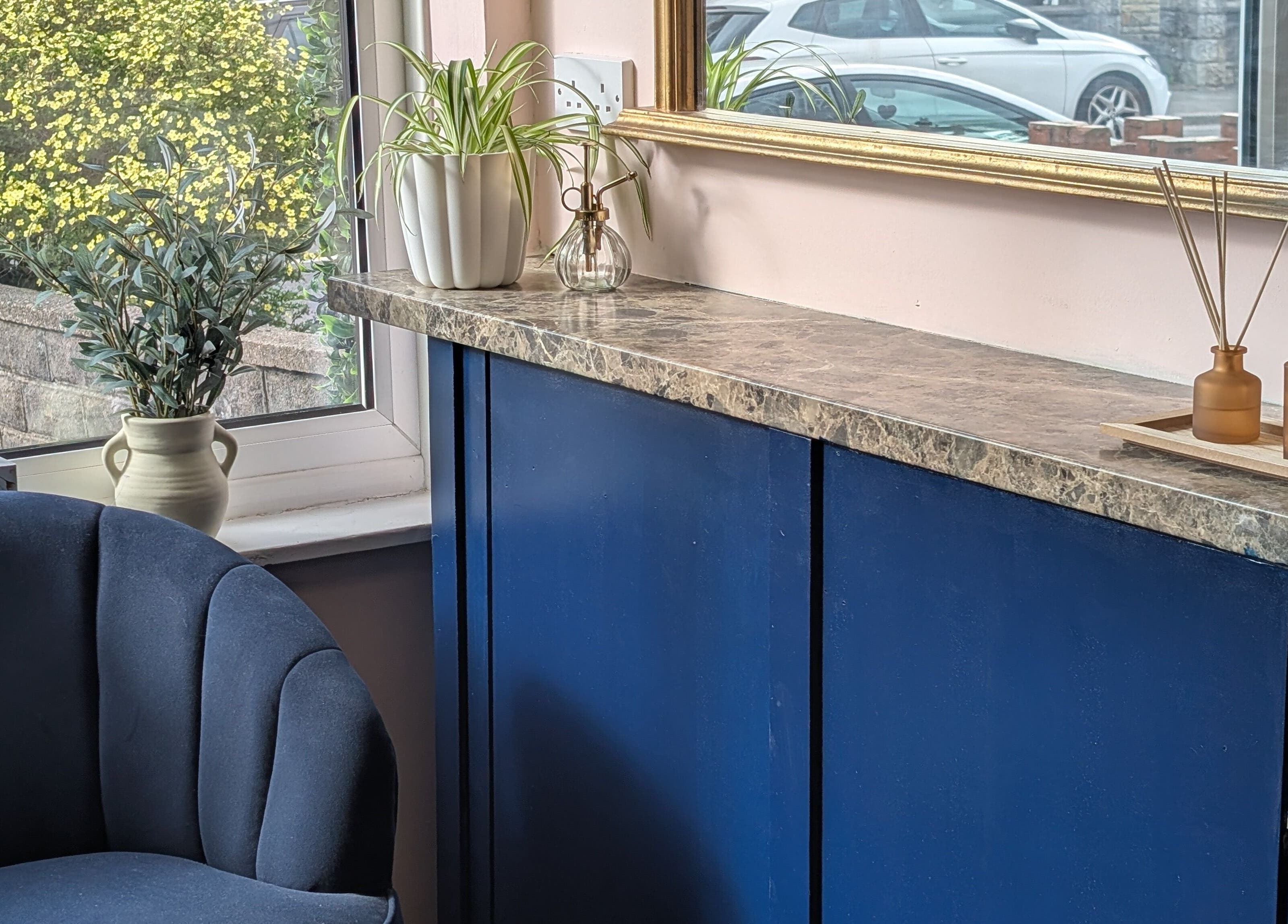 Cozy corner at Ona in Tonna, Wales with blue seating and elegant decor by the window.