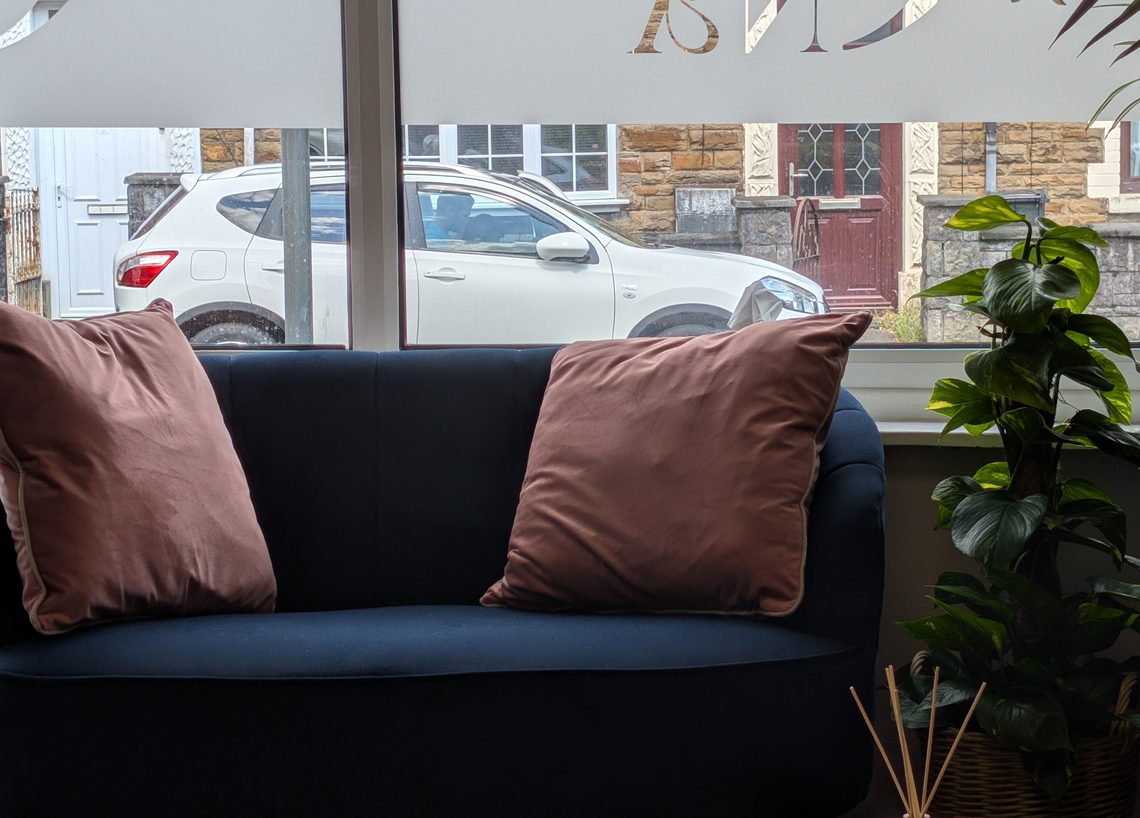 Cozy seating area at Ona, Tonna, Wales, GB with plush cushions and greenery beside a window.