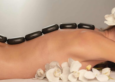 Massage aux pierres chaudes chez Massage ejm, Nouméa, Province Sud, NC avec fleurs blanches apaisantes.