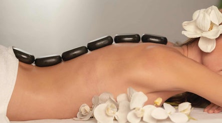 Massage aux pierres chaudes chez Massage ejm, Nouméa, Province Sud, NC avec fleurs blanches apaisantes.