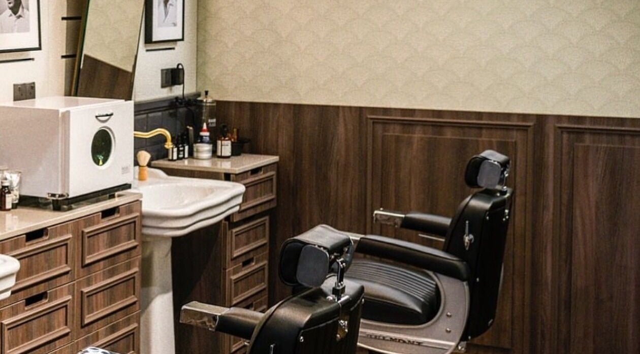 صالون Bull Frog الحديث في مسقط، محافظة مسقط، مزود بمقاعد حلاقة أنيقة وتفاصيل خشبية فاخرة.