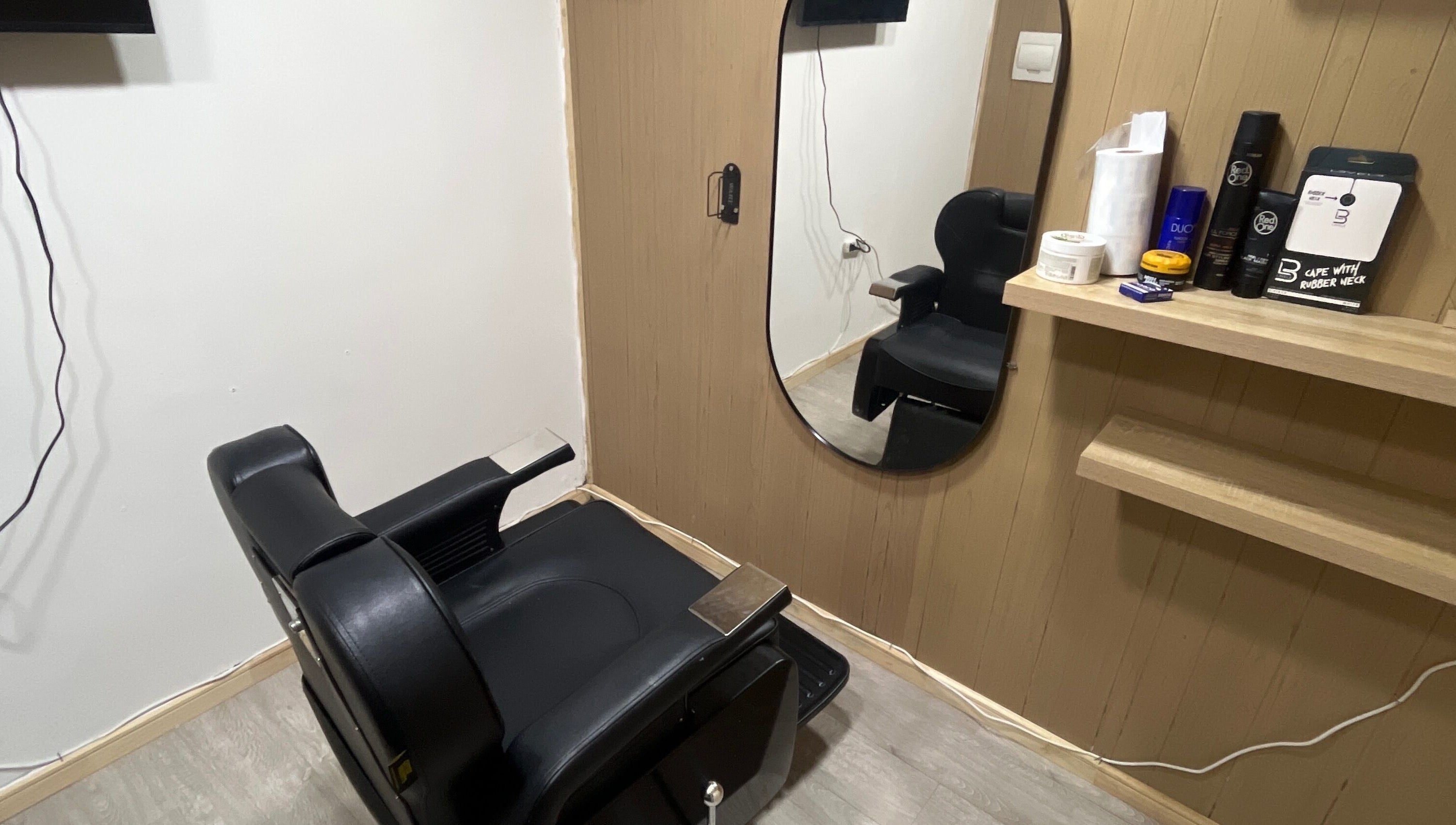 Sala de peluquería moderna en Thony Estilo, Puerto Montt, Los Lagos, CL. Sillón negro y espejo elegante.