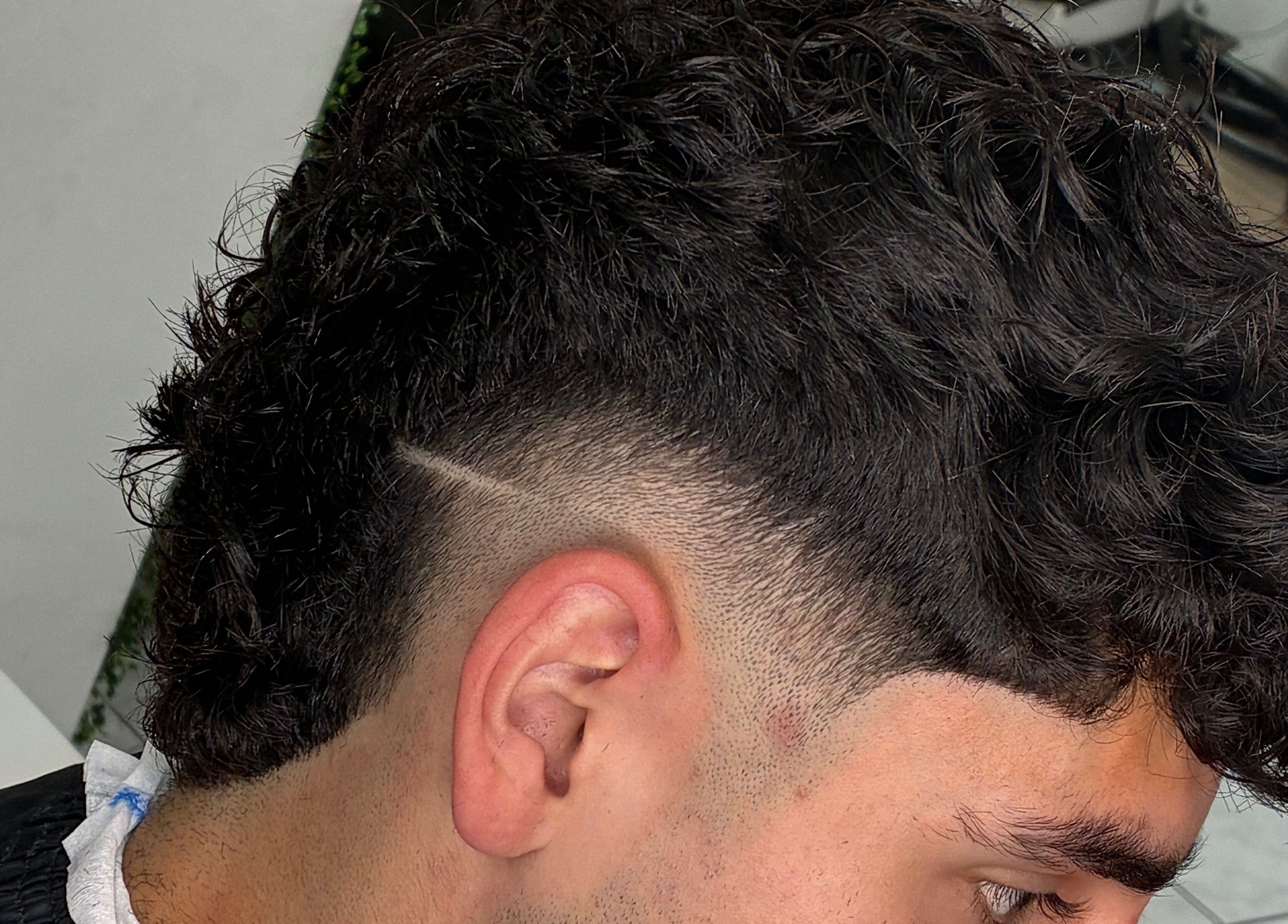 Corte de pelo moderno en Righo.99, Puerto Montt, Los Lagos, CL, con lados rasurados y rizos en la parte superior.