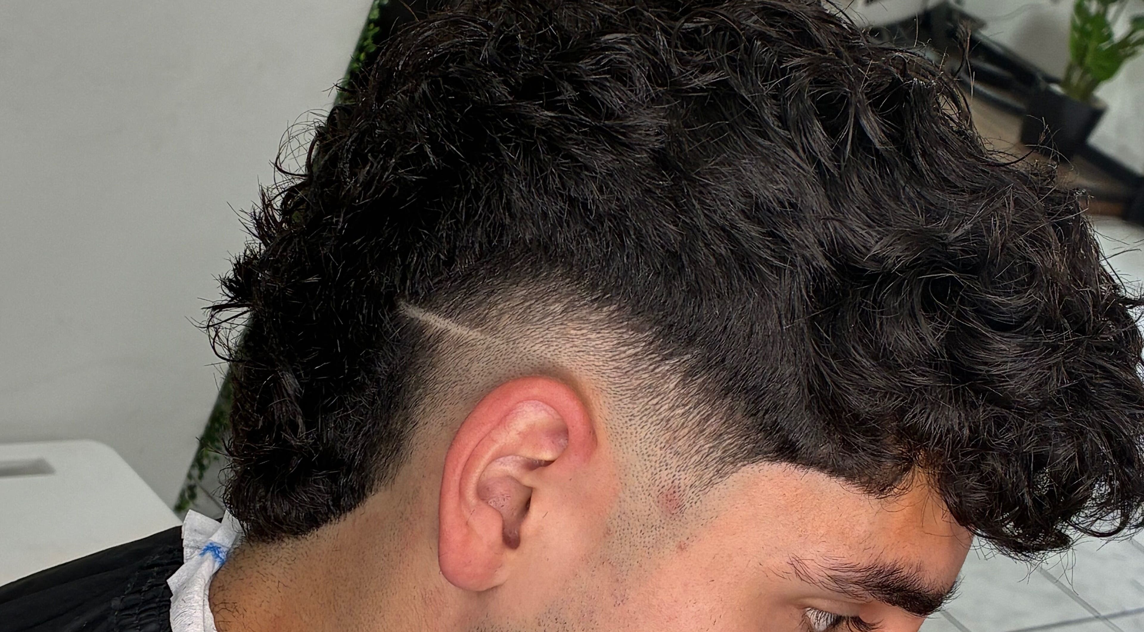 Corte de pelo moderno en Righo.99, Puerto Montt, Los Lagos, CL, con lados rasurados y rizos en la parte superior.