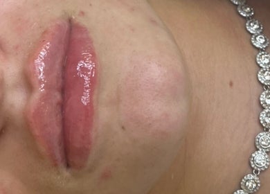 Close-up of glossy lips adorned with a necklace at Beauty & Aesthetics By Lil, Bradford, England, GB.