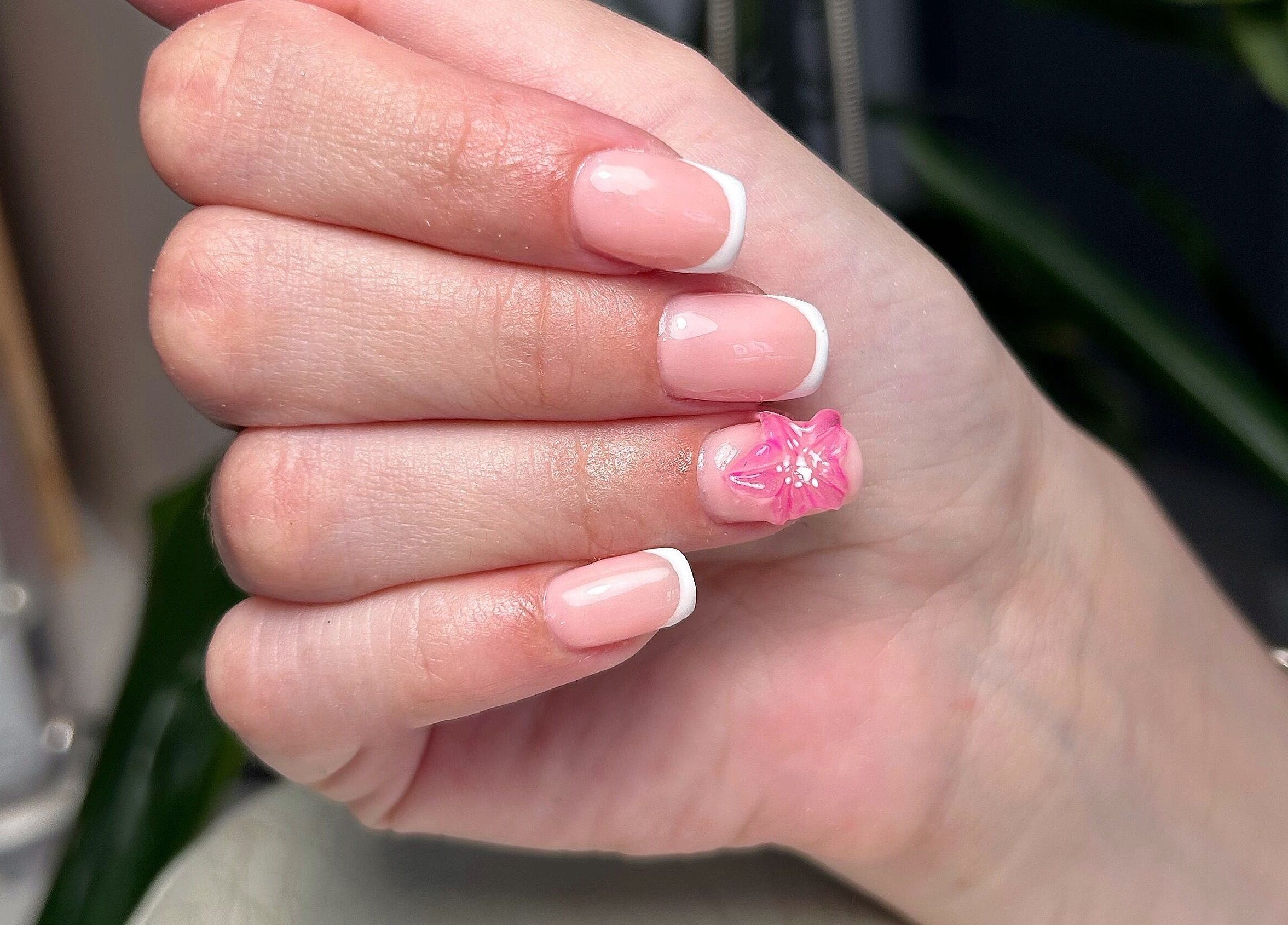 Nail art à L’onglerie de Lau à Castries, Occitanie, FR, avec une fleur rose et une manucure française élégante.