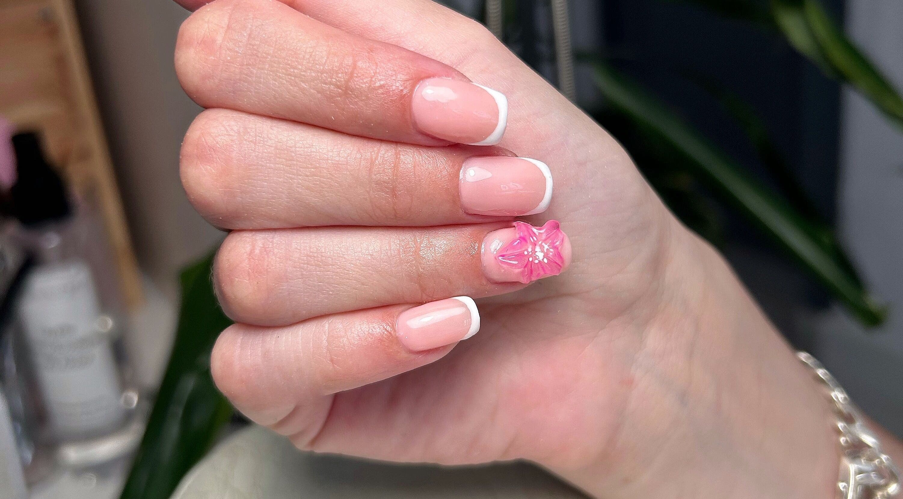 Nail art à L’onglerie de Lau à Castries, Occitanie, FR, avec une fleur rose et une manucure française élégante.