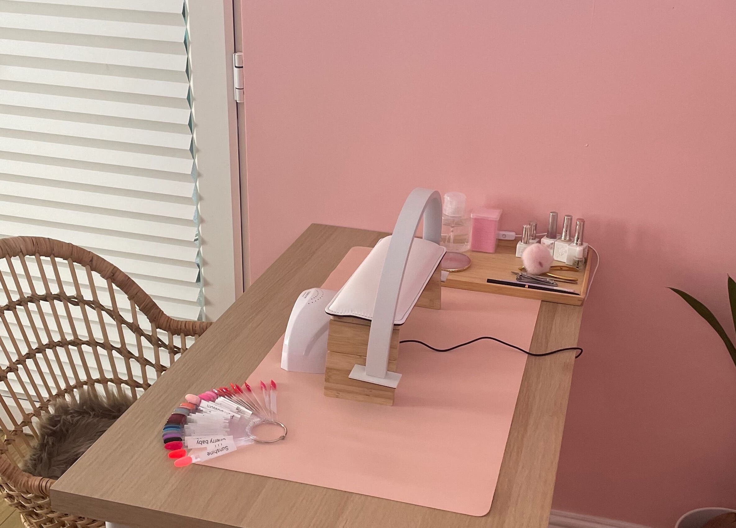 Elegant nail station at Lyndsay’s Beauty, Bottesford, England, GB with a cozy wicker chair and pink decor.