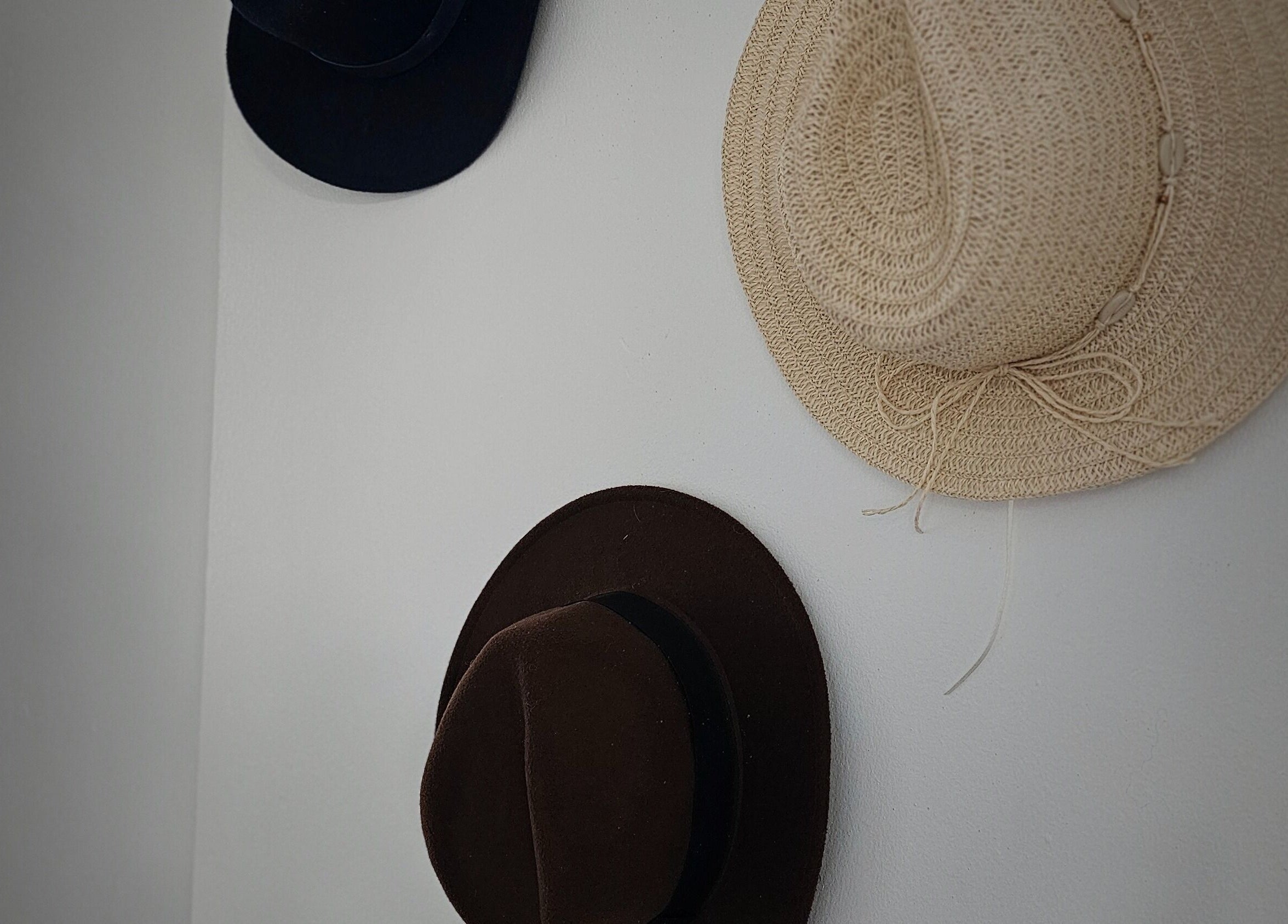 Three stylish hats adorn a wall in Taylor'd Hair, Catterick Garrison, England, GB, enhancing the salon's decor.