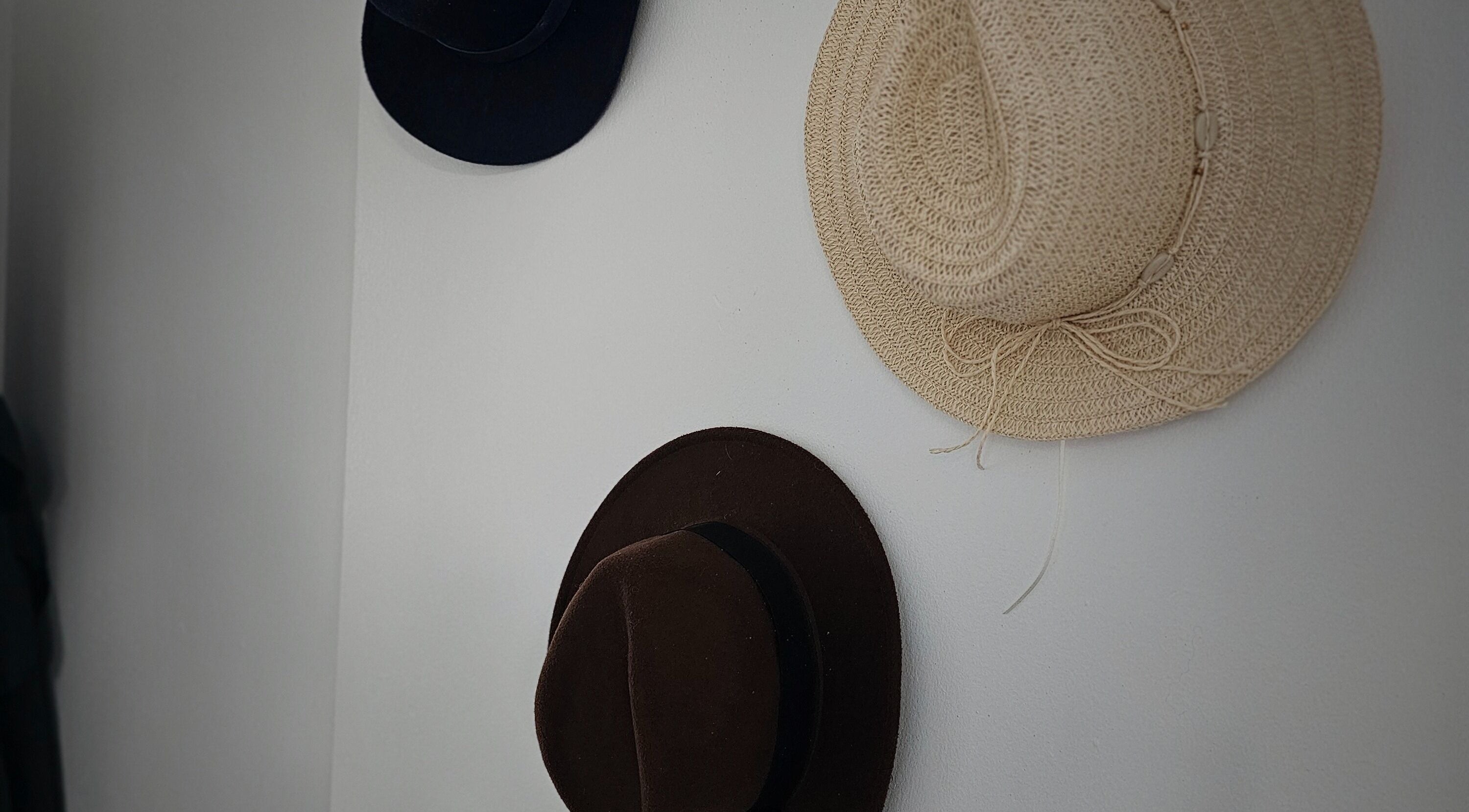 Three stylish hats adorn a wall in Taylor'd Hair, Catterick Garrison, England, GB, enhancing the salon's decor.