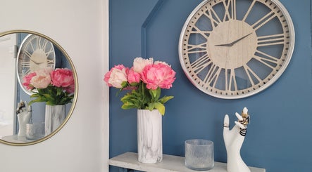 Décor élégant chez Magnifi'sens, Coubron, Île-de-France, avec horloge et fleurs roses en vase marbré.