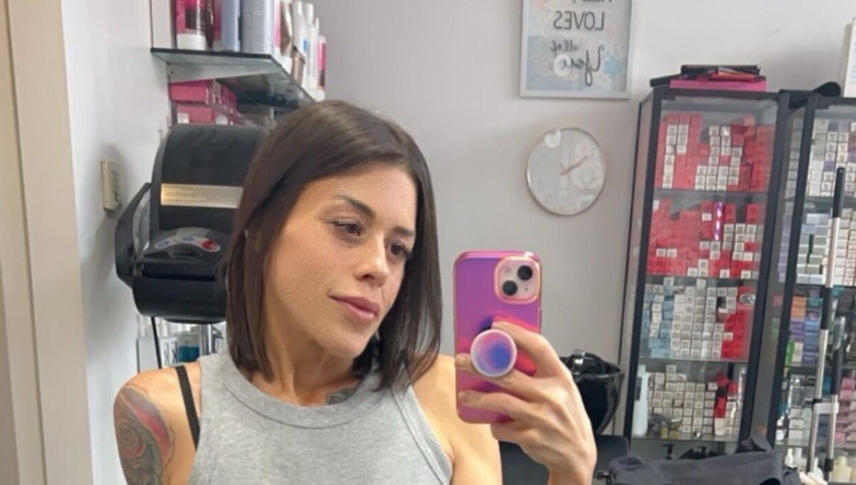 Client at Sheena McCart, Vancouver, BC, CA, takes a salon selfie in front of hair products.