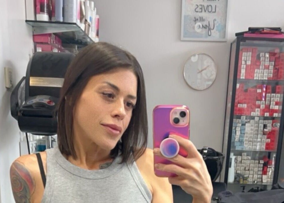 Client at Sheena McCart, Vancouver, BC, CA, takes a salon selfie in front of hair products.